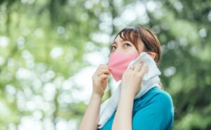 汗を拭うマスク姿の女性