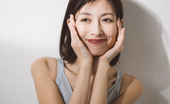 ほおづえをついてほほえむ女性