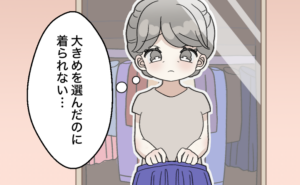 クローゼットの前で服を手にしながら「大きめを選んだのに着られない…」と悩む女性が困った表情をしている様子。
