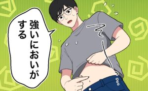 自分の Tシャツの裾をまくり上げて、おへその近くにある小さな黒い点を指で触ろうとしながら「強いにおいがする」と困惑している男性。