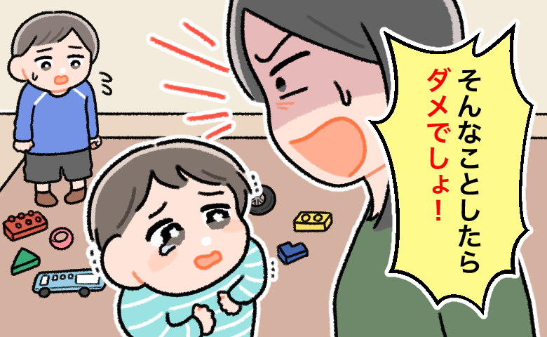おもちゃが床に散らかる室内で、1歳の息子を「そんなことしたらダメでしょ！」と怒る母親。怒られた子どもは涙を浮かべて怯えており、背後で兄と思われる年長の子が心配そうに見つめている